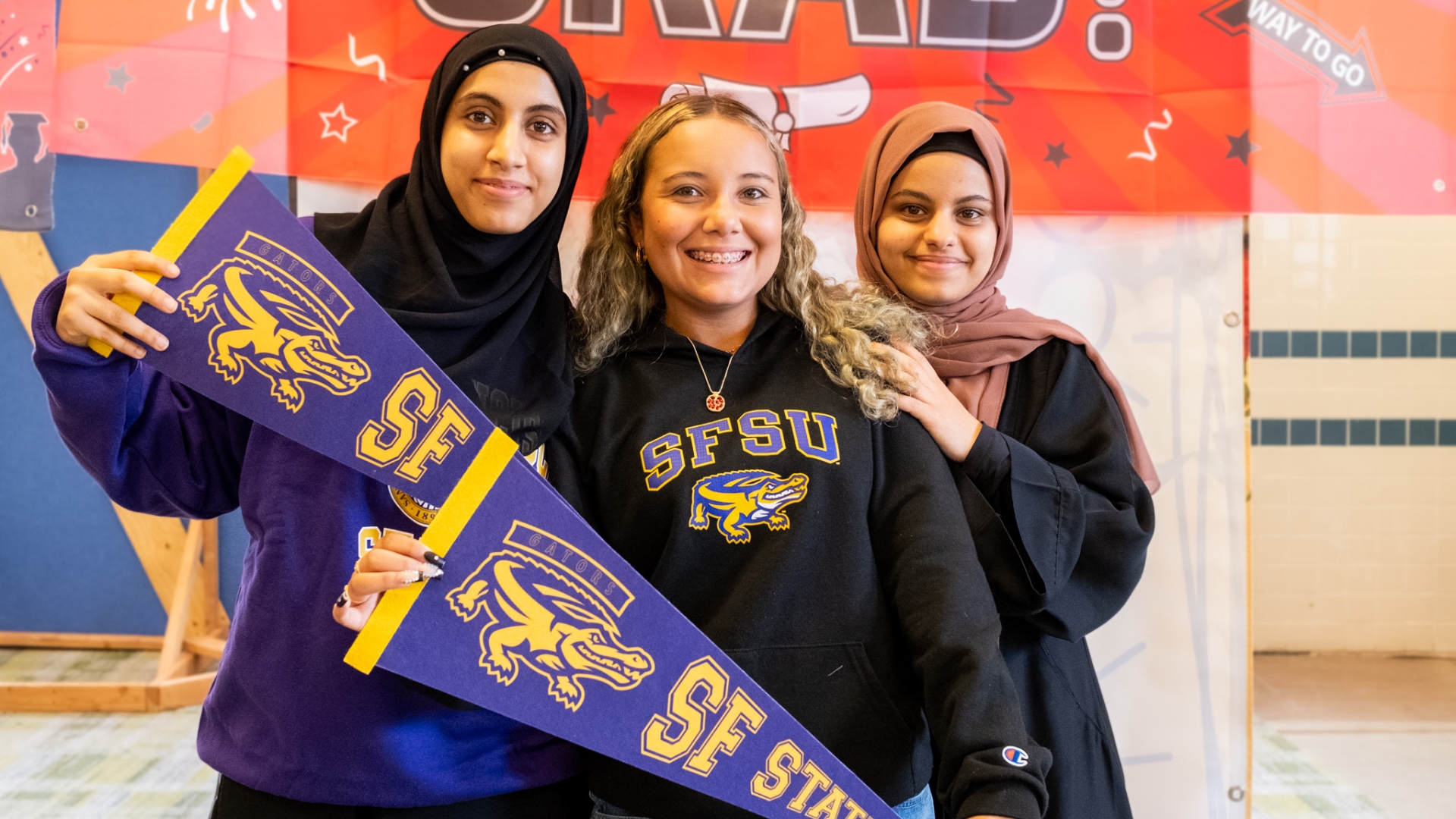 Three female students holding a team flag