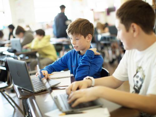 two male students working on a laptop