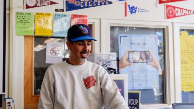 Teacher speaks in front of college flags