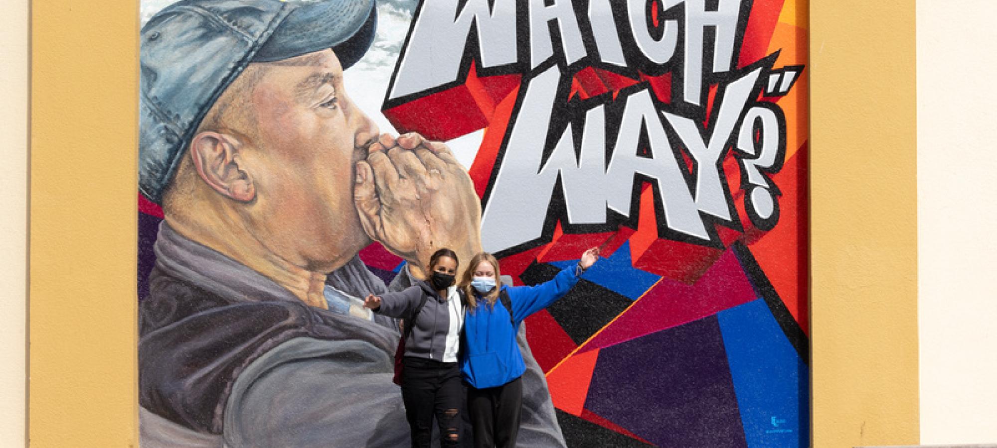 students pose in front of mural
