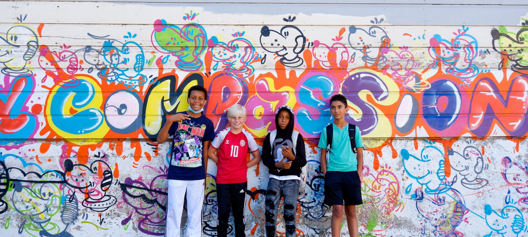 boys pose in front of a mural