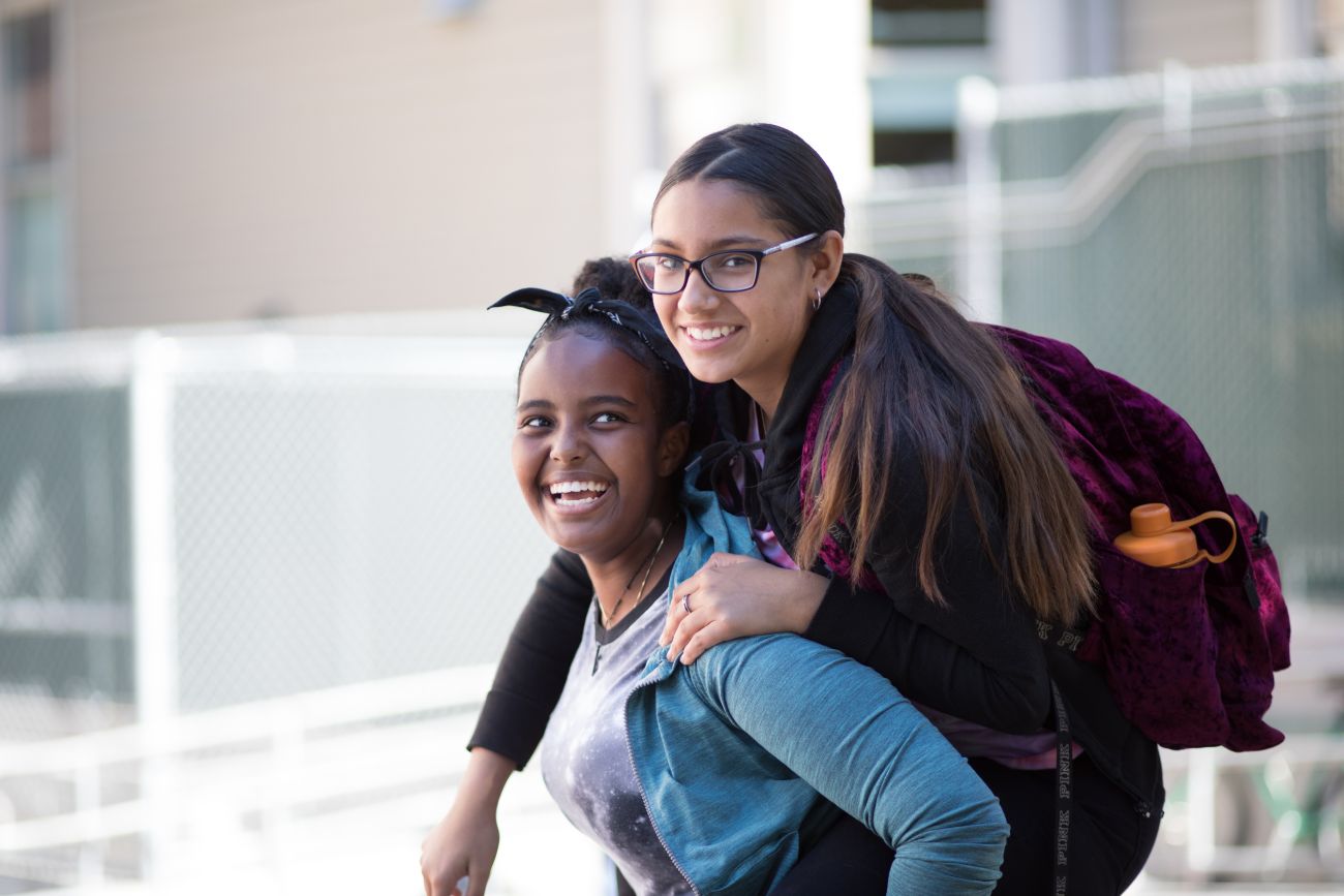 Two smiling girls, one carrying the other